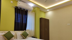 A hotel room with a bed, a wardrobe, an air conditioning unit, and a window with curtains. - The Nirvana Resort (Chatra)