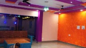 A room with a blue sofa, a ceiling fan, and a wall with a textured orange finish. - The Nirvana Resort (Chatra)