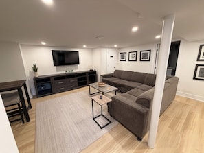 Un salon moderne avec un canapé, un téléviseur et un meuble de divertissement.