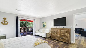 Una camera da letto con un letto, un comò in legno, una TV e un balcone con un ombrellone rosso.