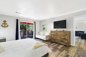 Ein Schlafzimmer mit Bett, einem Holzschrank, einem Fernseher und einem Balkon mit einem roten Sonnenschirm.
