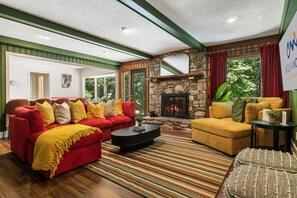 A living room with a stone fireplace, red and yellow sofas, and a striped rug.