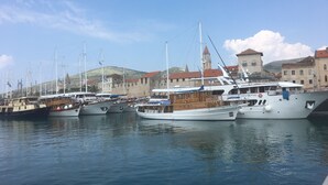 Un port de plaisance avec plusieurs bateaux amarrés, un bâtiment historique en arrière-plan et un ciel dégagé.