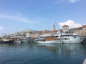 Ein Yachthafen mit mehreren dort angestuerten Booten, ein historisches Gebäude im Hintergrund und ein klarer Himmel.