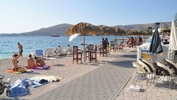 Une plage avec des transats, des parasols et un bateau en arrière-plan.