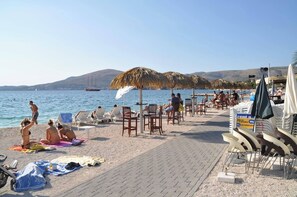 A beach with sun loungers, umbrellas, and a boat in the background. - Apartment Jenny with Pool,   pet-friendly (Okrug Gornji)