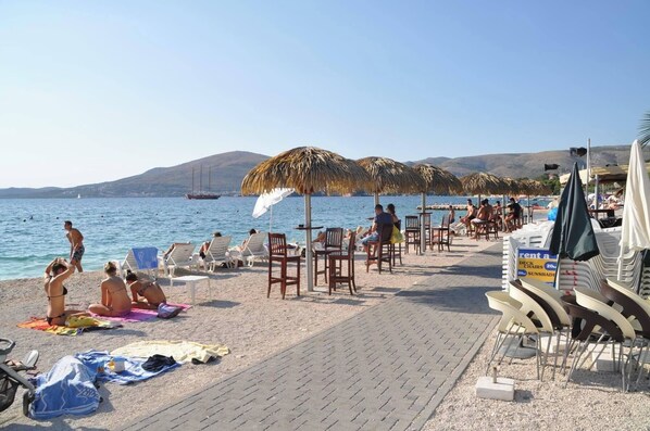Ein Strand mit Liegestühlen, Sonnenschirmen und einem Boot im Hintergrund.