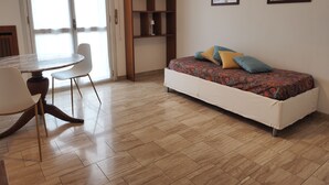 A room with a bed, a dining table with chairs, a bookshelf, and two framed pictures on the wall. - Three-room apartment de Angeli area (Milano)