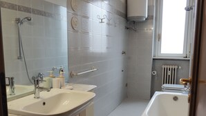 A bathroom with two sinks, a shower, a bathtub, and a window. - Three-room apartment de Angeli area (Milano)