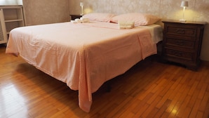 A neatly made bed with a pink bedspread, two bedside tables with lamps, and a wooden dresser. - Three-room apartment de Angeli area (Milano)