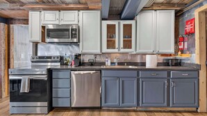 Una cocina moderna con electrodomésticos de acero inoxidable, armarios grises y piso de madera.