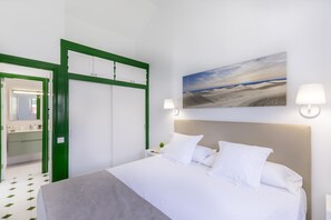 Una habitación de hotel con una cama, una mesita de noche, una lámpara, un cuadro y un armario con marco verde.