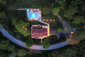 Eine Luftaufnahme eines Hauses mit Pool, Terrasse und Auffahrt.