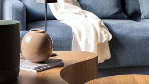 A modern living room with a blue sofa, a round wooden coffee table, a vase, and a floor lamp. - Room-cozy City Cottage With Sauna, hot t (Espoo)