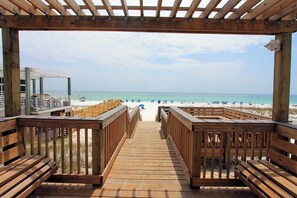 Eine Holzterrasse führt zu einem Strand mit freiem Blick auf das Meer.