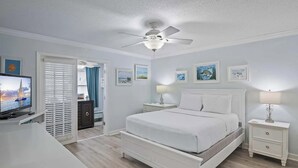 A bedroom with a bed, a ceiling fan, a TV, and artwork on the walls. - Pet Friendly | Steps to Beach | Pool | Chateau La Mer 13A (Destin)