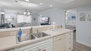 A modern kitchen with a built-in sink, a ceiling fan, and a television. - Pet Friendly | Steps to Beach | Pool | Chateau La Mer 13A (Destin)