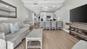 A modern living room with a sofa, coffee table, and TV stand. - 🐚Walk to Beach | Pool | Henderson Beach Resort Lofts 104- Poolside Paradise🐬 (Destin)
