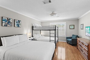 Un dormitorio con una cama litera, un escritorio, una silla, un aparador y obras de arte en las paredes.