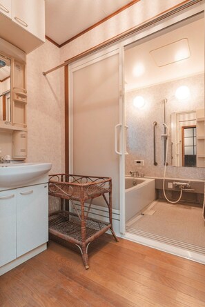 Une salle de bain avec une douche, un lavabo et une chaise en osier.