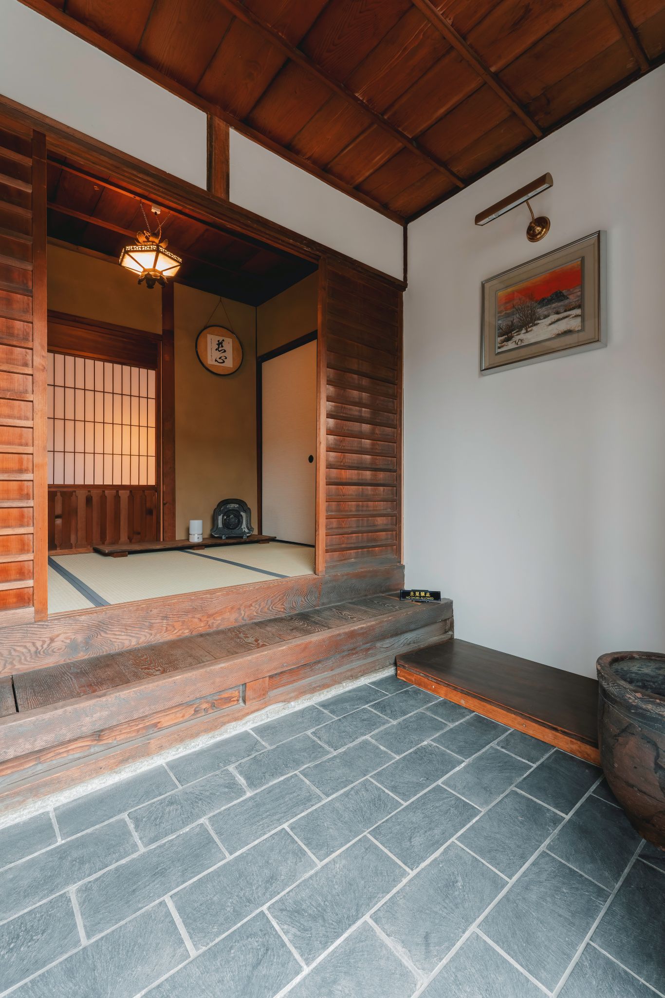 A traditional Japanese room with tatami flooring, a wooden ceiling, and a sliding door.