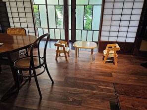 Ein traditioneller japanischer Raum mit Tatami-Boden, einem niedrigen Tisch und einer Schiebetür mit Blick auf Grünflächen.