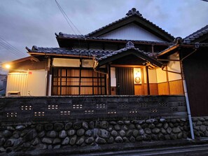 A traditional Japanese building with a tiled roof, wooden lattice windows, and a stone wall.