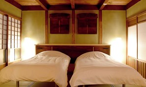Ein Zimmer mit zwei Betten, Holz-Kopfteilen und einem traditionellen japanischen Shoji-Bildschirm.
