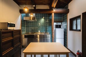 Une cuisine compacte avec une table en bois, des appareils en acier inoxydable et un dosseret de carrelage vert.