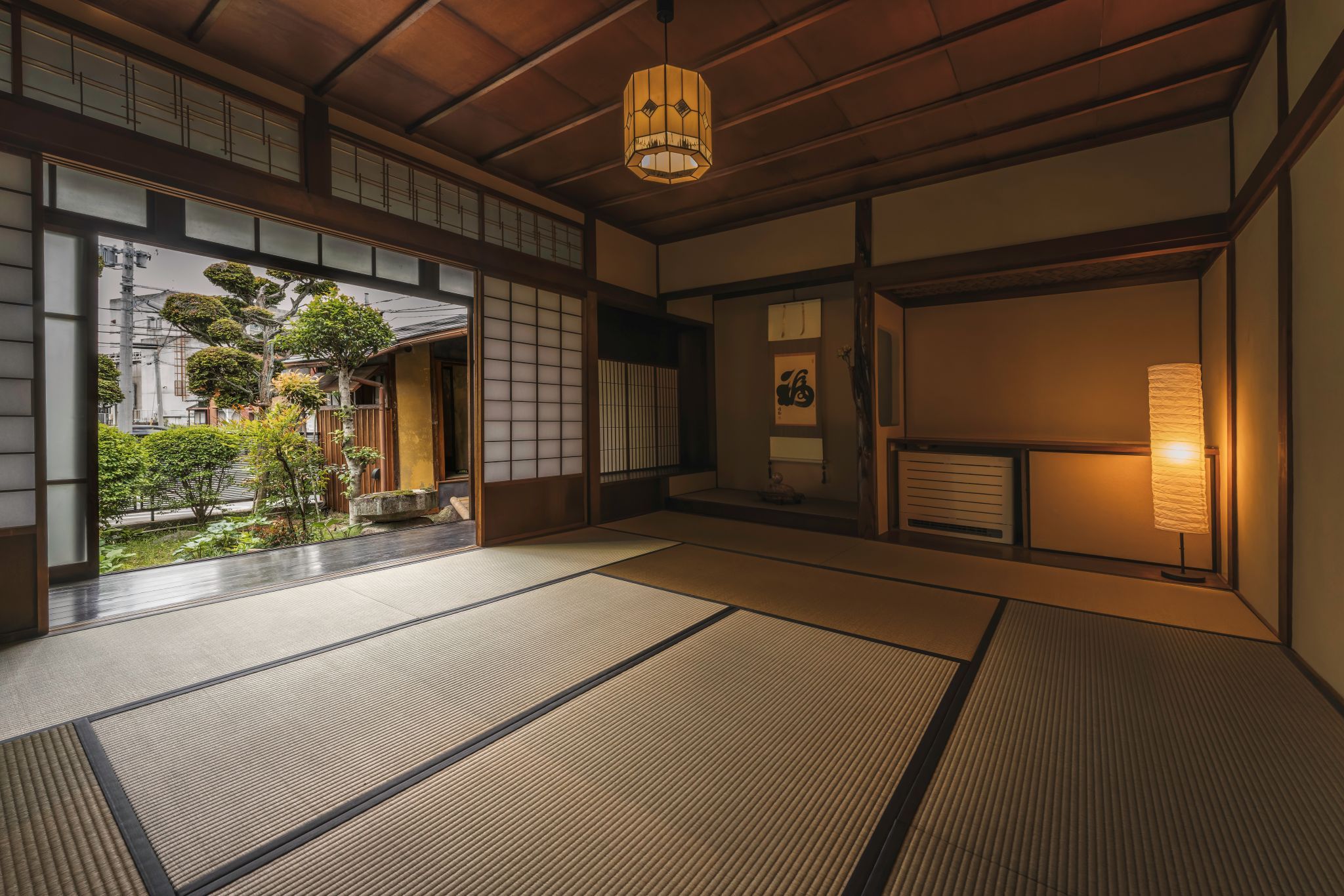 A traditional Japanese room with tatami flooring, sliding doors, and a view of a garden.