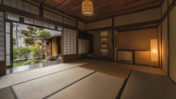 A traditional Japanese room with tatami flooring, sliding doors, and a view of a garden.