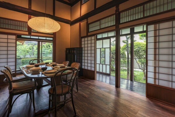 Une pièce de style japonais traditionnel, avec un sol recouvert de tatamis, une table basse avec des coussins et des portes coulissantes.