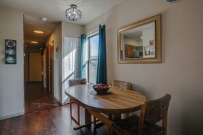 A dining area with a wooden table, chairs, a bowl of fruit, and a mirror on the wall. - Condo close to hiking trails and base area (Angel Fire)
