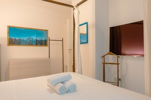 Ein Hotelzimmer mit Bett, Gemälde, Spiegel, Fernseher und Kleiderschrank.