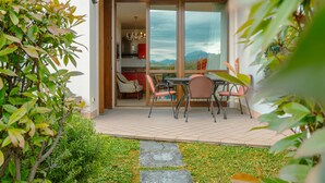 Een terras met een tafel en stoelen, uitzicht op de bergen en een deur die leidt naar een kamer met een kroonluchter.