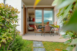 Eine Terrasse mit Tisch und Stühlen, mit Blick auf die Berge, und eine Tür zu einem Zimmer mit einem Chandelier.