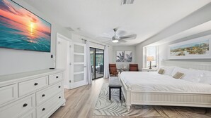 Une chambre à coucher avec un lit, une commode, un ventilateur de plafond et un grand tableau accroché au mur.