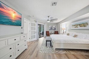 Ein Schlafzimmer mit Bett, Schminktisch, Deckenventilator und einem großen Gemälde an der Wand.