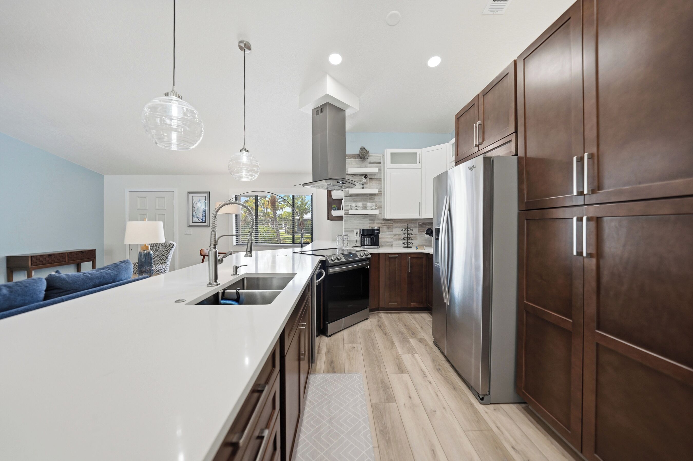 A modern kitchen with a central island, stainless steel appliances, and wooden cabinets.
