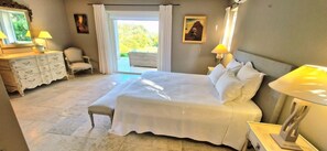 Een slaapkamer met een bed, een dressoir, een stoel en een raam met gordijnen.