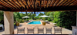 A covered outdoor area with a swimming pool, lounge chairs, and umbrellas. - SUPERB MEDITERRANEAN VILLA 12 Pers SEA VIEW & ST TROPEZ, close to BEACHES & GOLF (Grimaud)