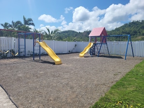 A playground with two slides and a red-roofed play structure.