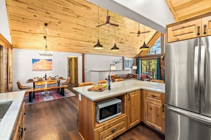Een moderne keuken met houten keukenkastjes, roestvrijstalen apparatuur en hanglampen.