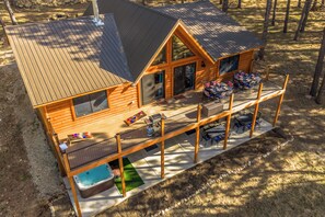 Eine Blockhütte mit Terrasse, Sitzgelegenheit im Freien und Whirlpool.