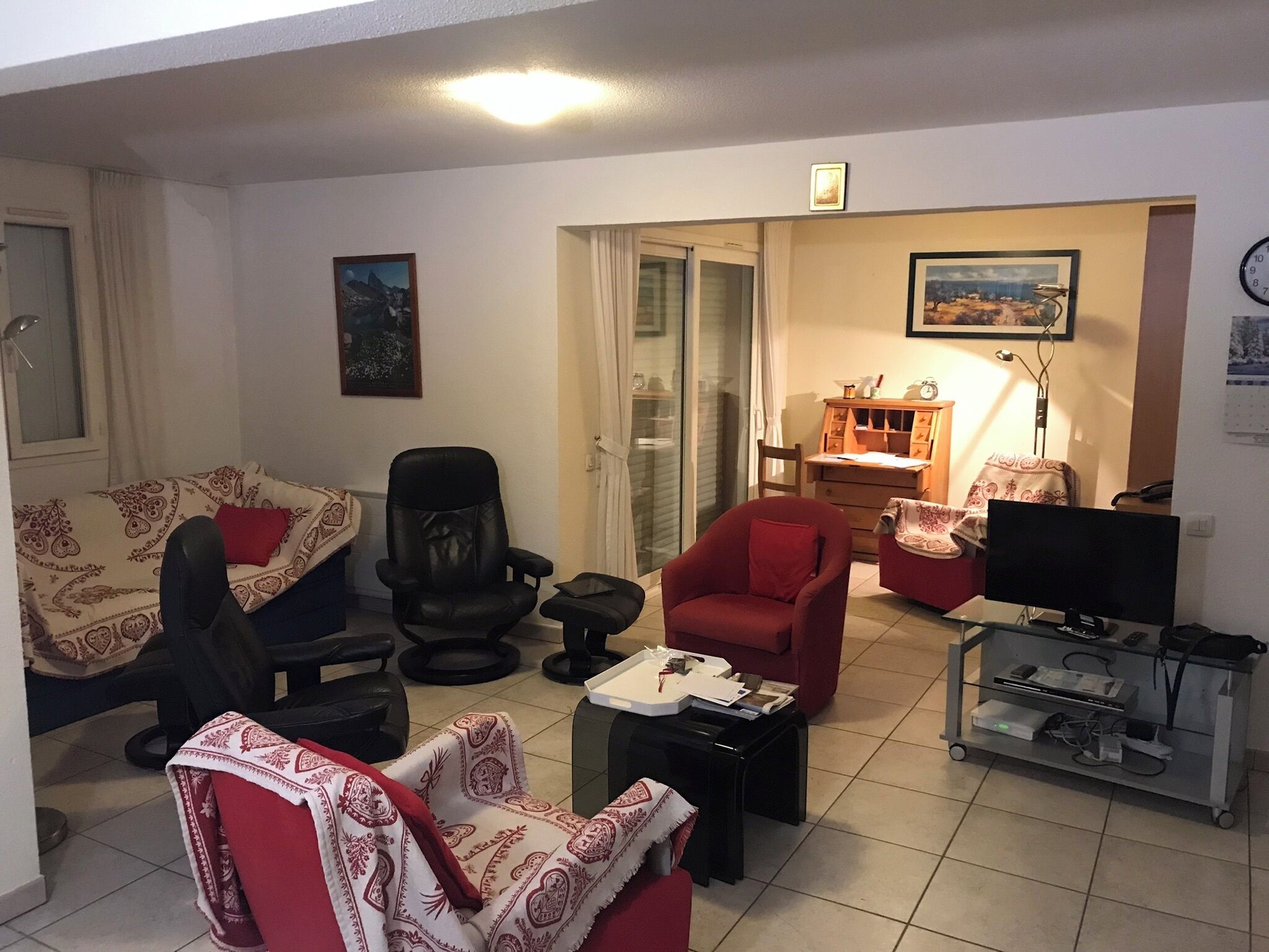A living room with a sofa, chairs, a desk, a television, and a computer setup.
