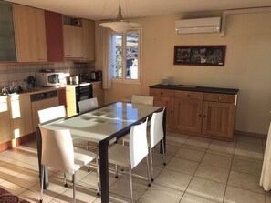 A kitchen with a dining table, chairs, cabinets, a microwave, and a window. - LARGE APARTMENT near historic center, shops and train station (Embrun)