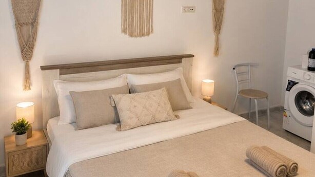 Ein ordentlich eingerichtetes Schlafzimmer mit Bett, Nachttischlampen, einer Waschmaschine und Wanddekoration.