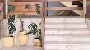 En trappa med ett träräcke och beige trappsteg, som leder upp till en liten plattform med en krukväxt.