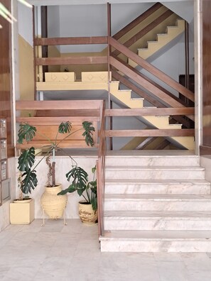 Eine Treppe mit einem Holzgeländer und beigefarbenen Stufen, die zu einem Zwischenpodest mit einem Blumentopf führt.