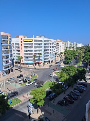 Ein mehrstöckiges Gebäude mit Balkonen, einem Parkplatz und blauem Himmel.